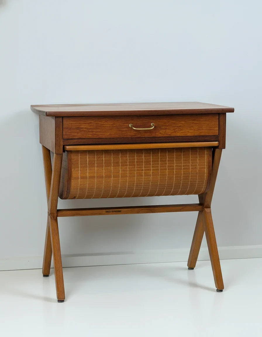 Mid-century modern wooden sewing table with drawer and fabric basket against white wall