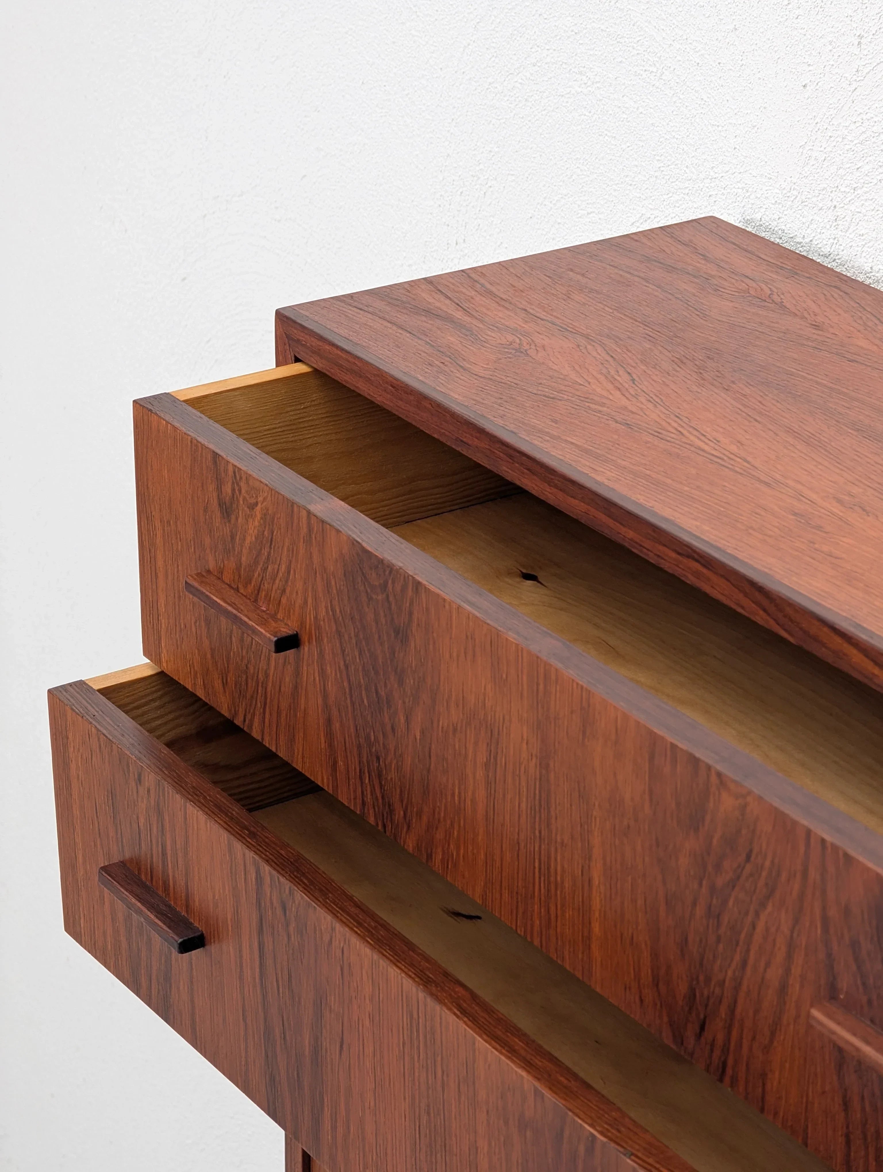 Mid-century modern wood dresser with two open drawers against a white wall