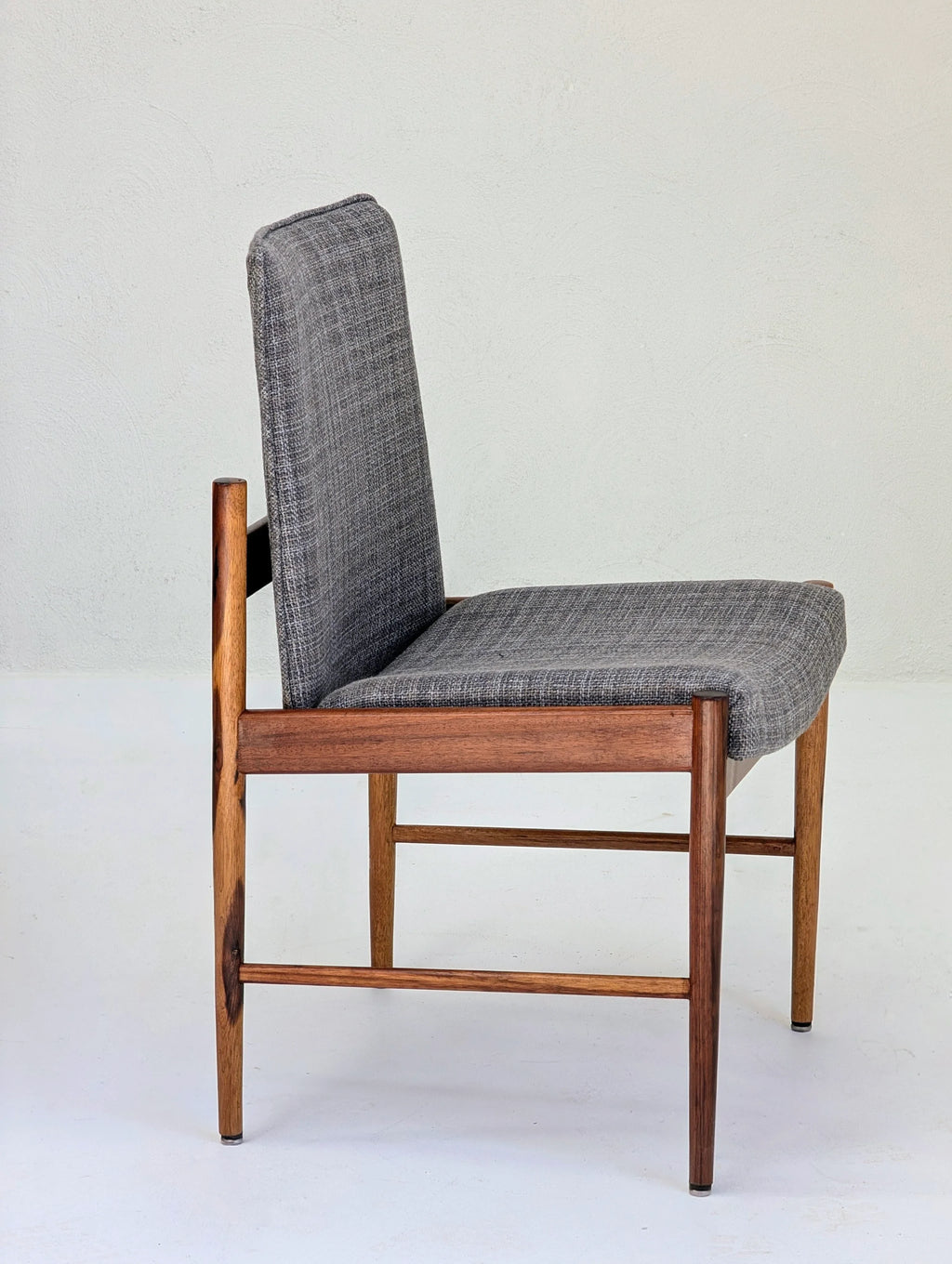 Side view of mid-century modern wooden chair with gray upholstered seat and backrest