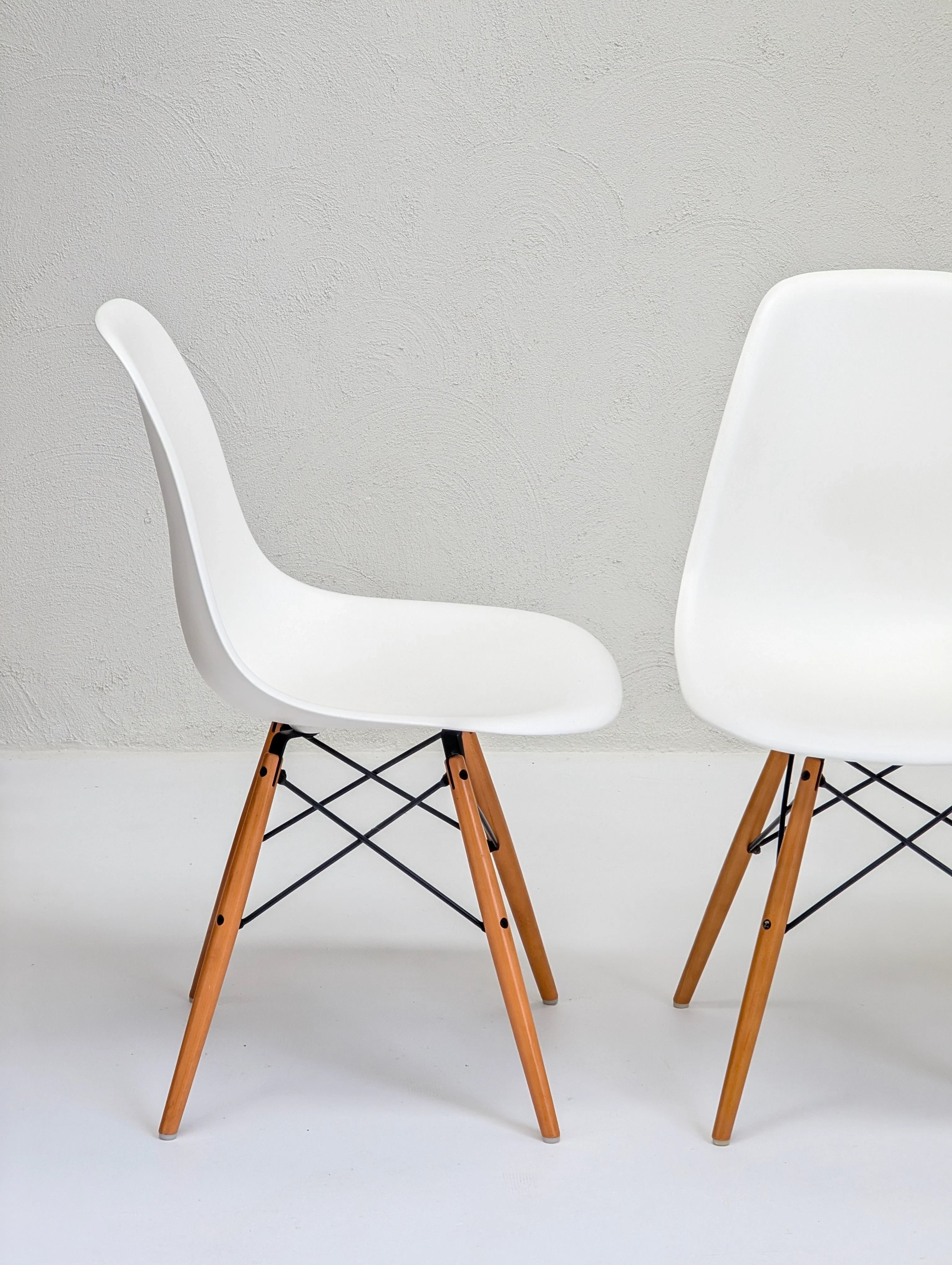 Modern white plastic chairs with wooden legs on a minimalist white background