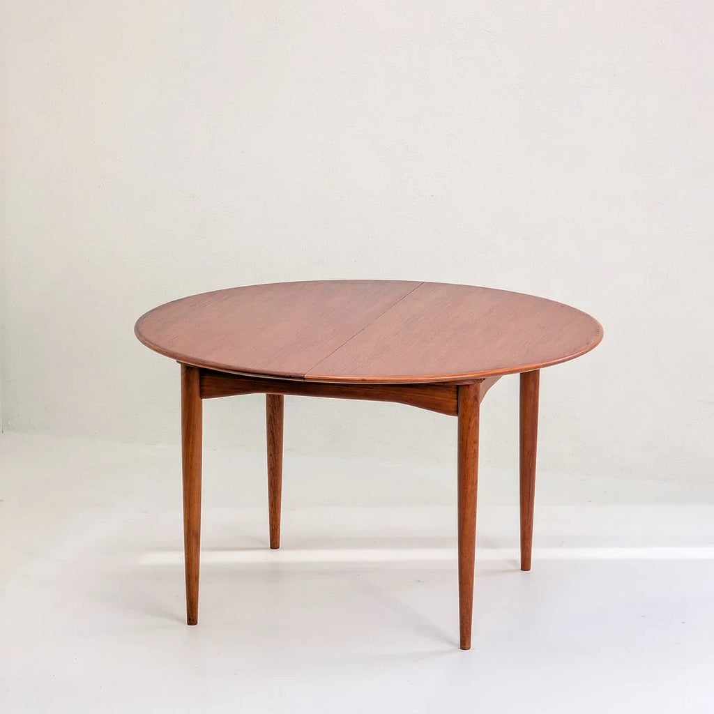Mid-century round wooden dining table with tapered legs on white background