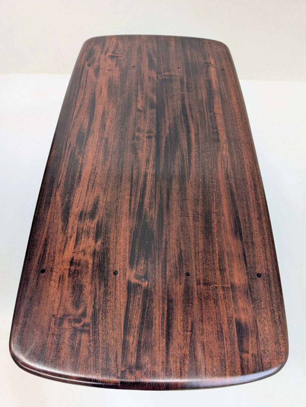 Top view of polished dark wood tabletop with natural grain pattern and rounded edges