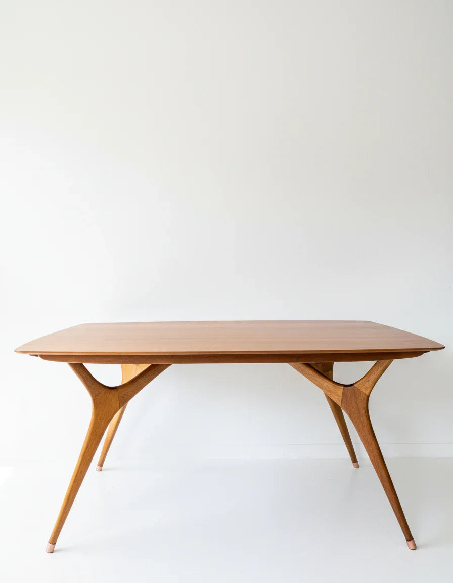 Elegant mid-century modern wooden dining table with sculptural angled legs on white background
