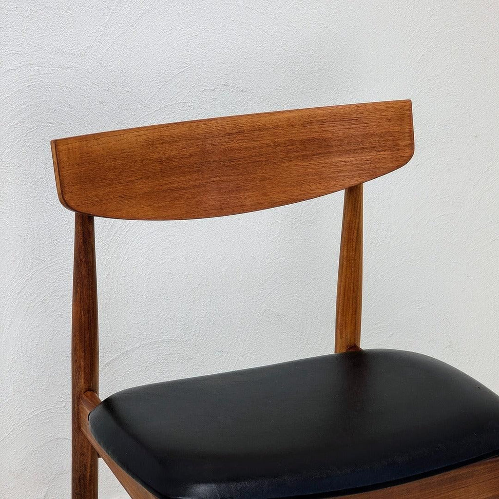 Mid-century teak dining chair with curved wooden backrest and black leather seat