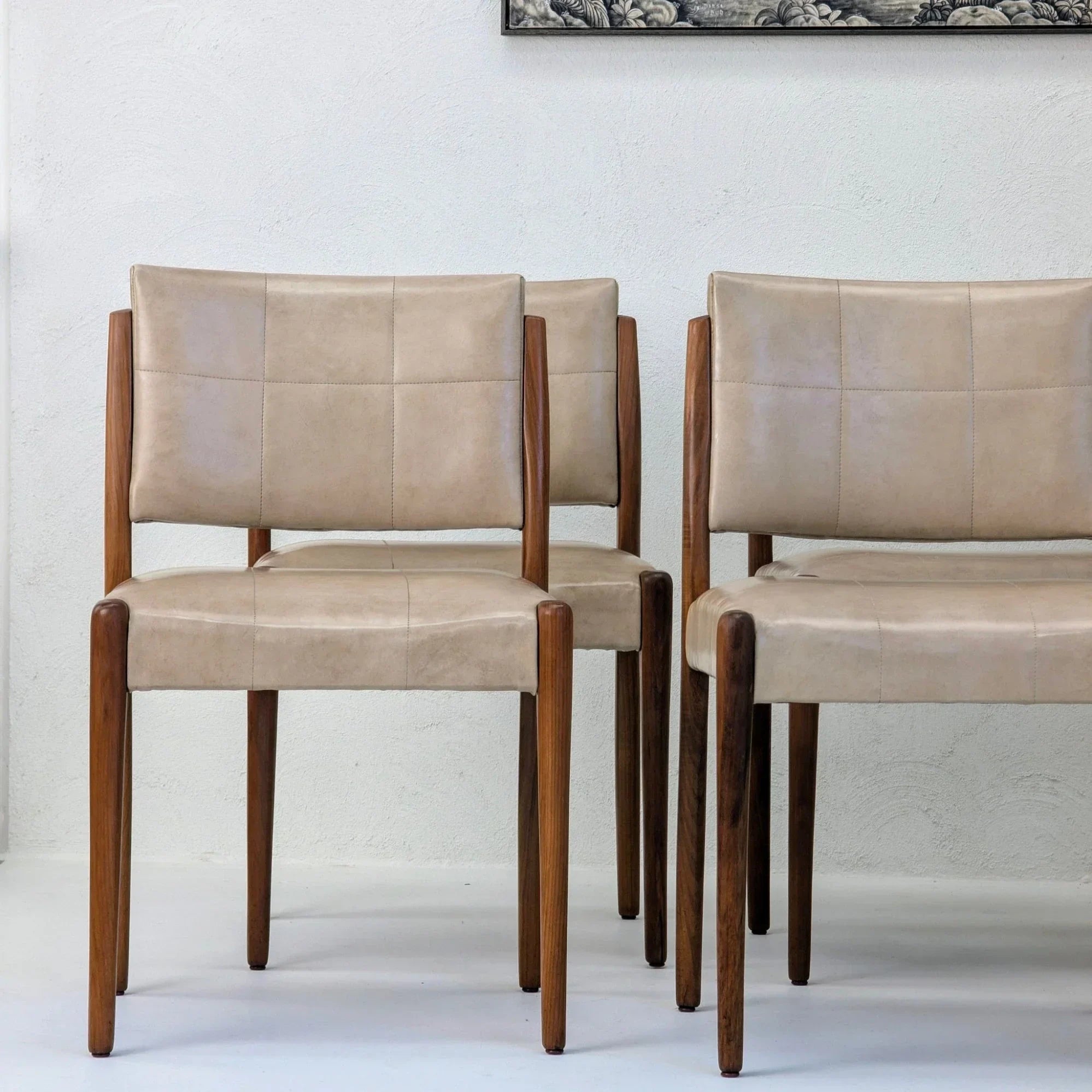 Set of six Fler dining chairs in Blackwood with beige leather upholstery against white wall