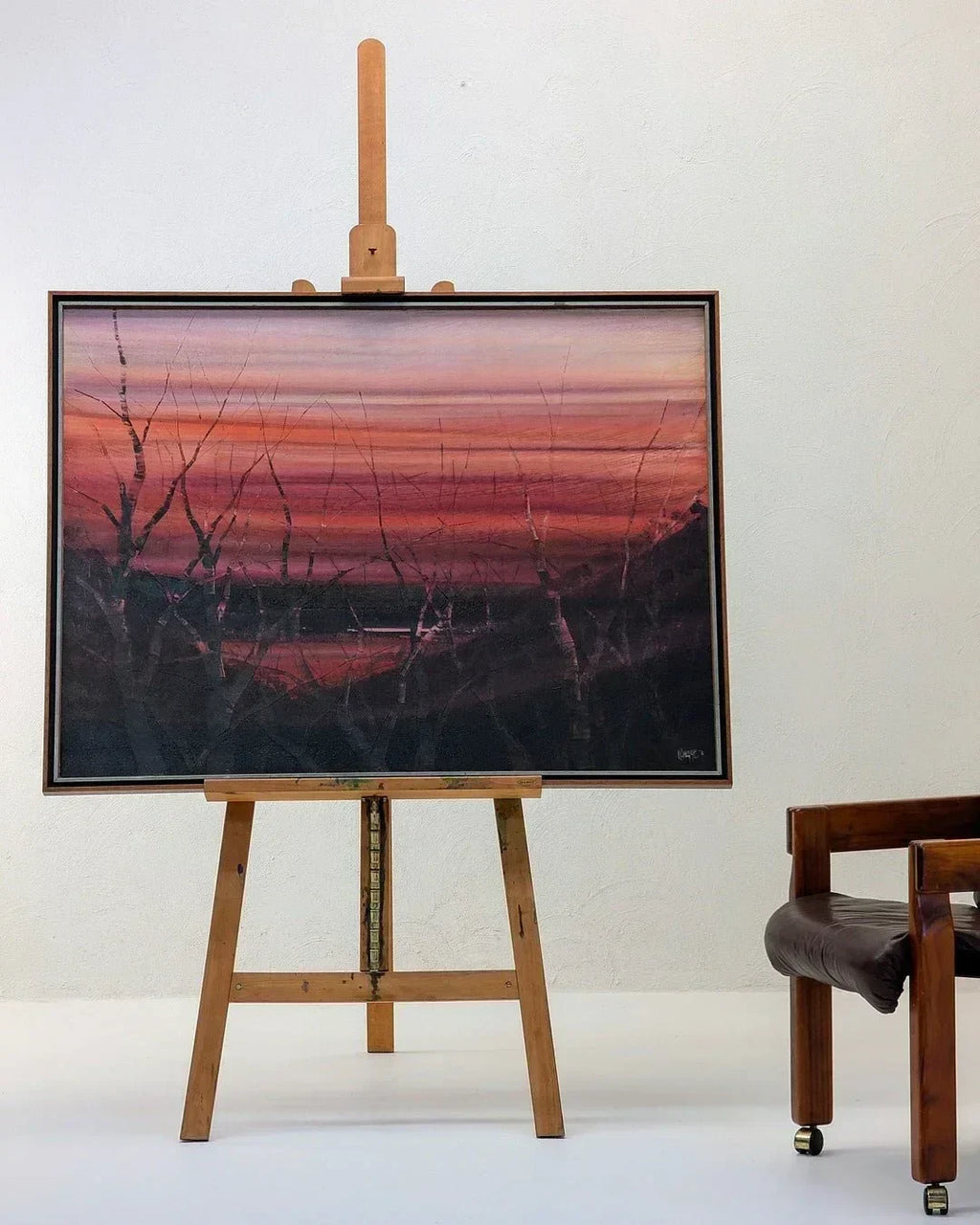 Wooden studio easel by Mabef Italy holding a framed landscape painting in a minimal room