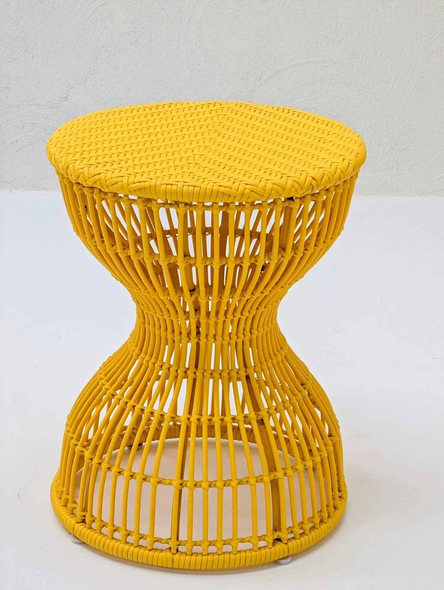 Yellow sculptural woven stool or side table with hourglass shape on white background