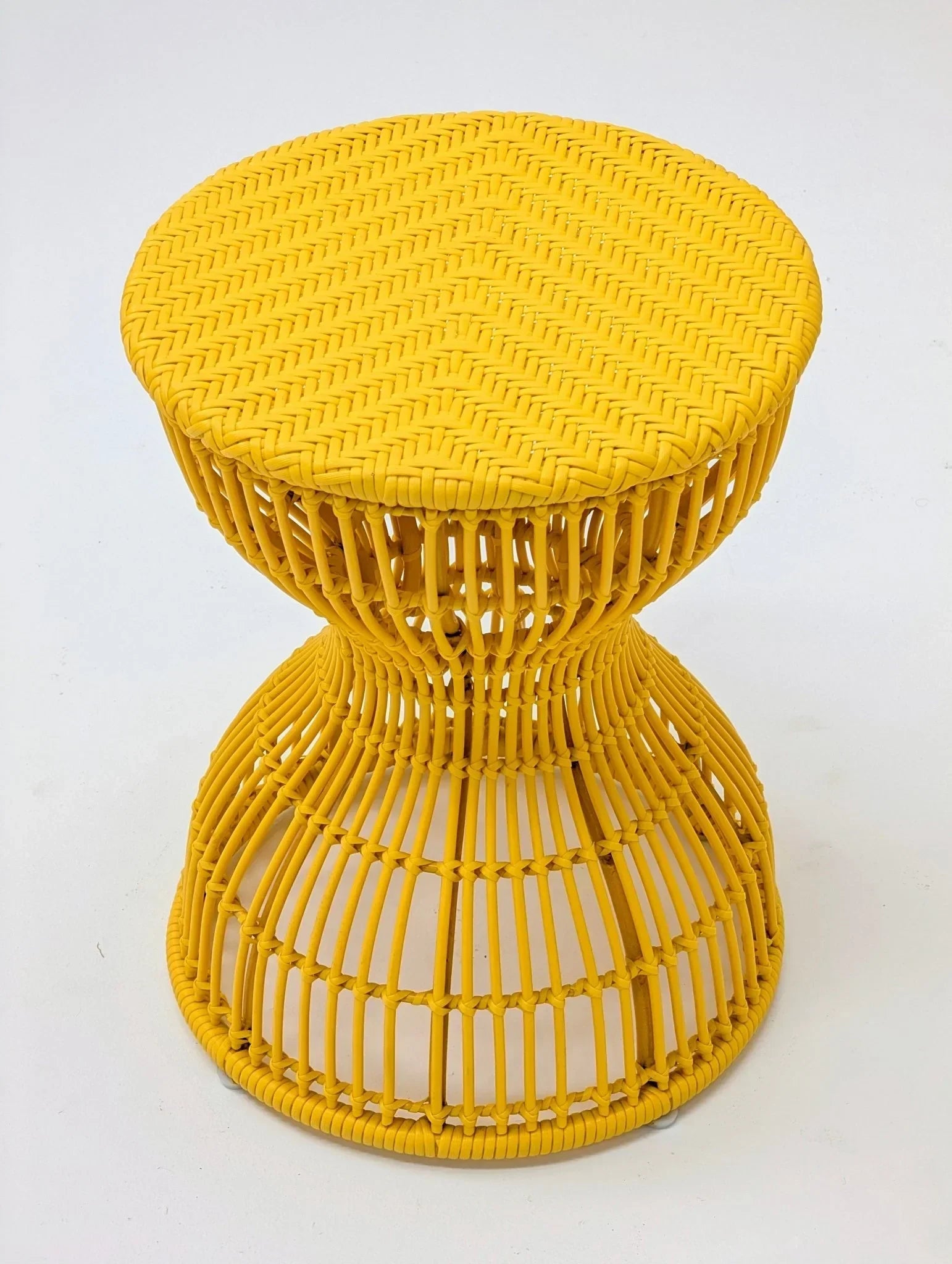 Yellow sculptural woven rattan stool or side table on white background