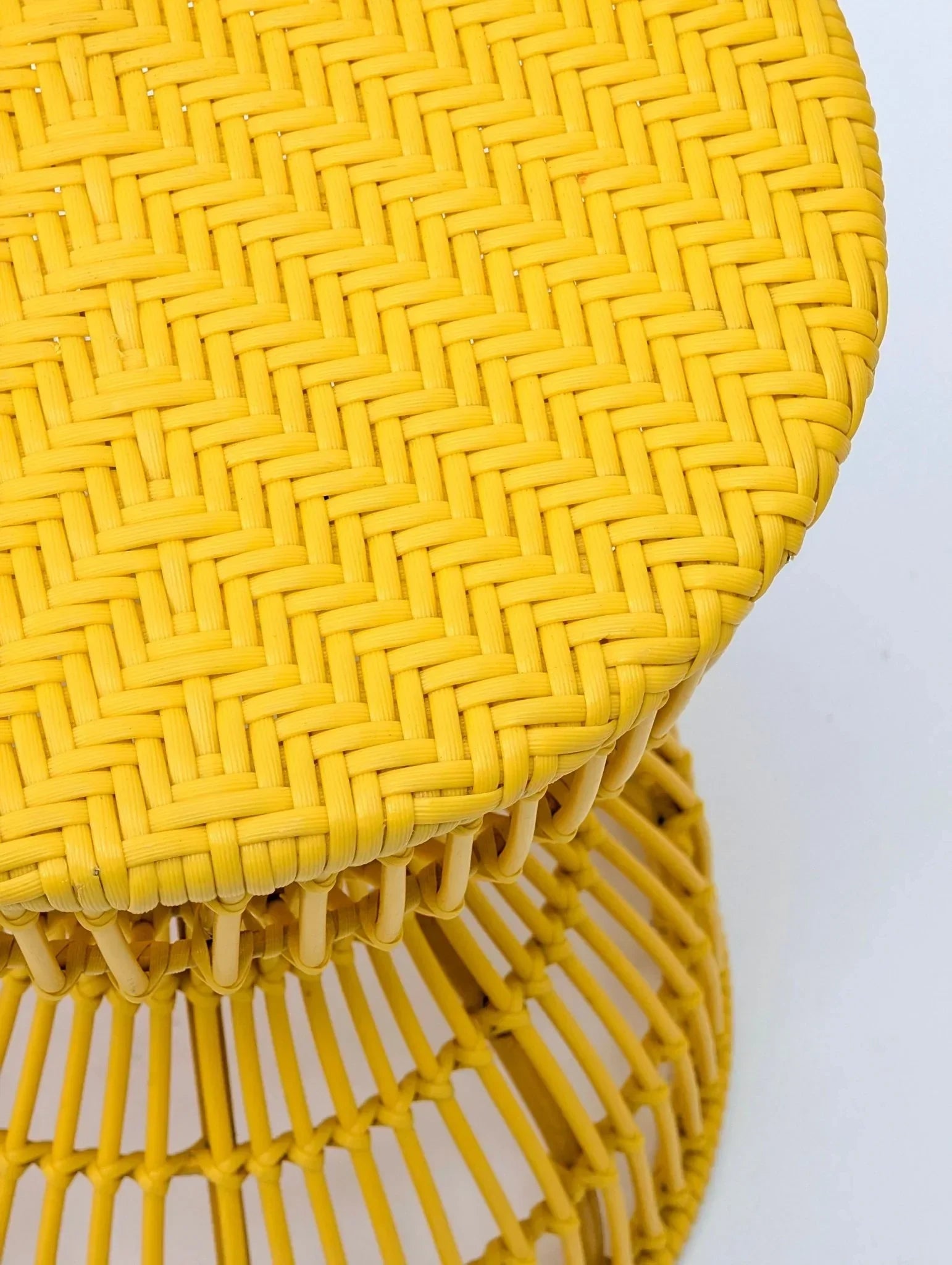 Yellow sculptural woven stool or side table with intricate rattan pattern on white background
