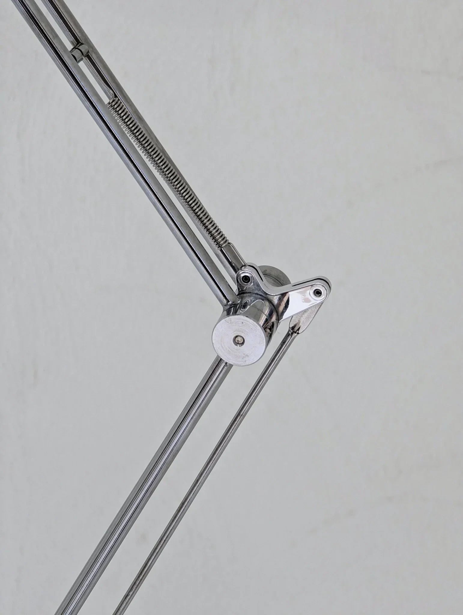 Close-up of vintage IKEA Antifoni floor lamp chrome arm and spring detail against plain wall