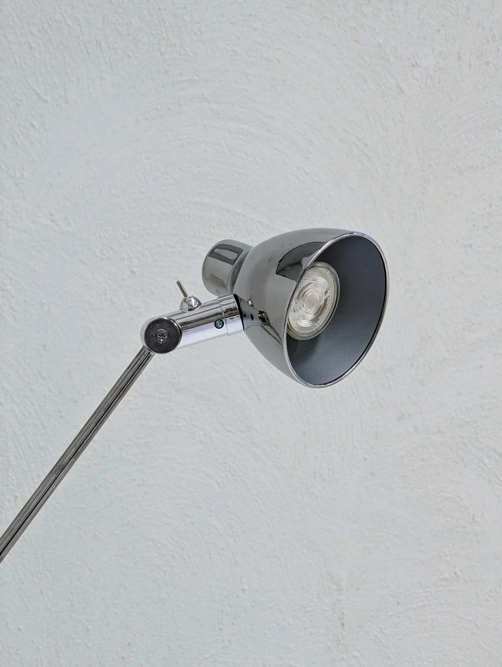 Vintage IKEA Antifoni chrome floor lamp close-up against textured white wall
