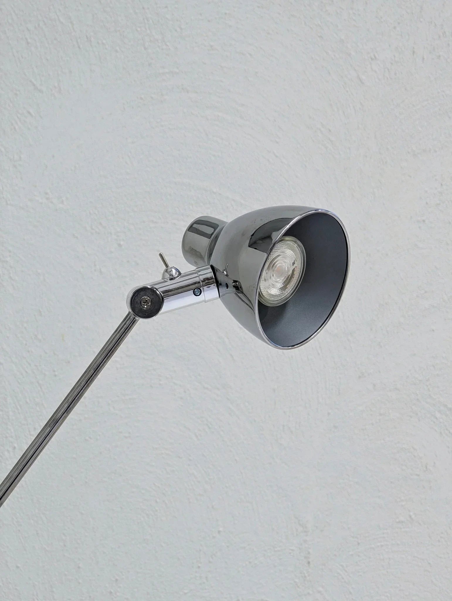 Vintage IKEA Antifoni chrome floor lamp close-up against textured white wall