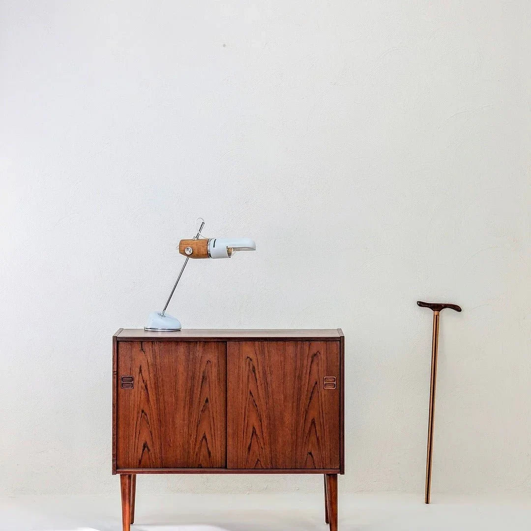 Vintage torpedo table lamp on mid-century wood cabinet next to walking cane